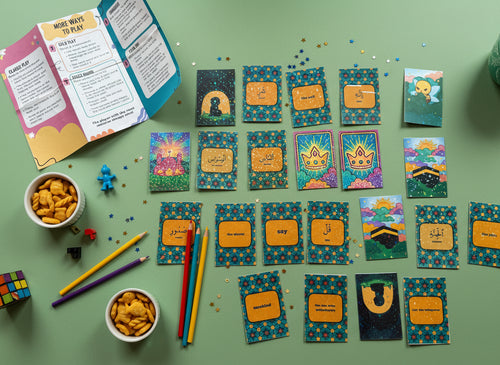 All 22 Qur'anic Arabic learning cards spread out with instruction booklet, snacks, colored pencils and toys on sage green background